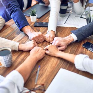 Group of business workers standing bumping fists at the office